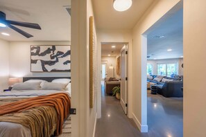 Een moderne hotelkamer met een groot bed, een plafondventilator en uitzicht op de woonruimte.