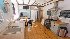 A kitchen with wooden flooring, a sink, a stove, and a trash can. - Streamways Slps 12-16 Hot Tub with Views & Cabin (Croyde)