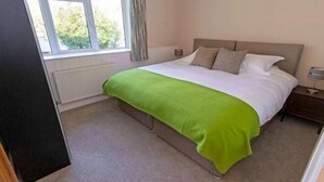 A bedroom with a bed, a window, a radiator, and a bedside table. - Streamways Slps 12-16 Hot Tub with Views & Cabin (Croyde)