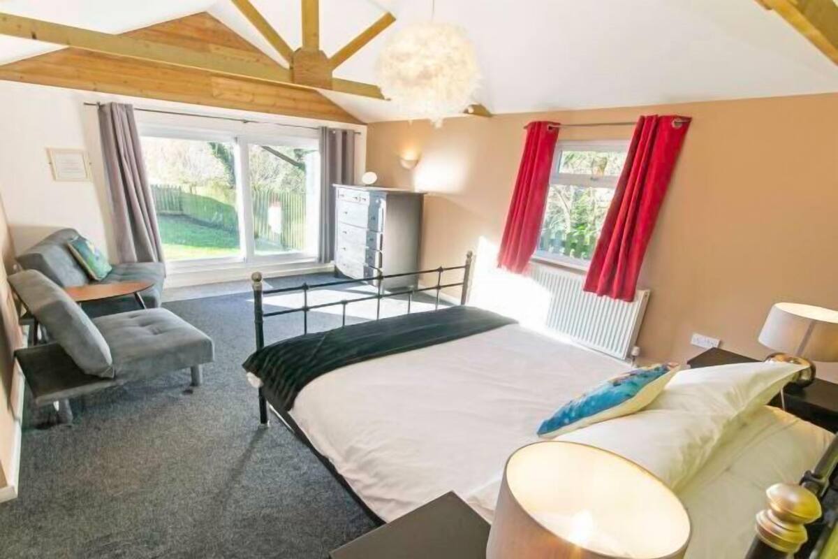 A bedroom with a bed, a desk, a chair, a dresser, and a window with curtains.