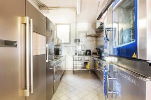 Une cuisine moderne dotée d’appareils électroménagers en acier inoxydable, d’un distributeur d’eau et d’un sol carrelé.