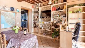 Ein gemütliches Zimmer mit Esstisch, Stühlen, einer Karte an der Wand und Regalen voller Bücher und Dekoartikeln.