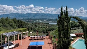 Eine Terrasse mit Sitzgelegenheiten im Freien, einem Pool und Blick auf Berge und einen See.