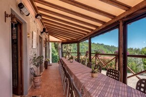 A covered outdoor dining area with a long table, chairs, and potted plants. - Private Country House with swimming pool -Chianti (Cavriglia)