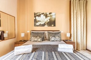 A hotel room with a large bed, two bedside tables, a nightstand, a wall-mounted lamp, and a framed picture of a flower. - Private Country House with swimming pool -Chianti (Cavriglia)