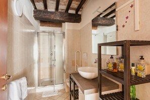 A bathroom with a glass shower, a white sink, and a shelf with toiletries. - Private Country House with swimming pool -Chianti (Cavriglia)