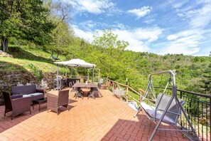 An outdoor patio with wicker furniture, a table, and a swing set. - Private Country House with swimming pool -Chianti (Cavriglia)