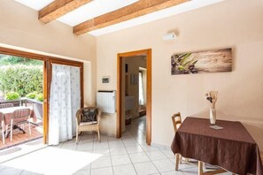A room with a dining table, chairs, a chair, a door leading to a balcony, and a painting on the wall. - Private Country House with swimming pool -Chianti (Cavriglia)