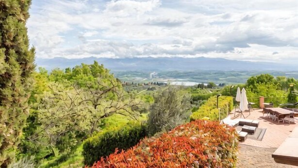 Eine Terrasse mit Sitzgelegenheiten im Freien, Blick auf die Landschaft und Bäume.