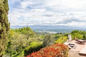 Eine Terrasse mit Sitzgelegenheiten im Freien, Blick auf die Landschaft und Bäume.