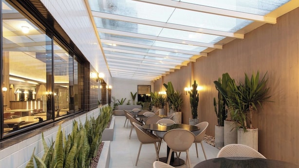 A modern indoor patio with a glass ceiling, seating area, and potted plants. - 2 Rooms, Triple Comfort in Downtown – Ideal for Friends or Big Families (Paraná)