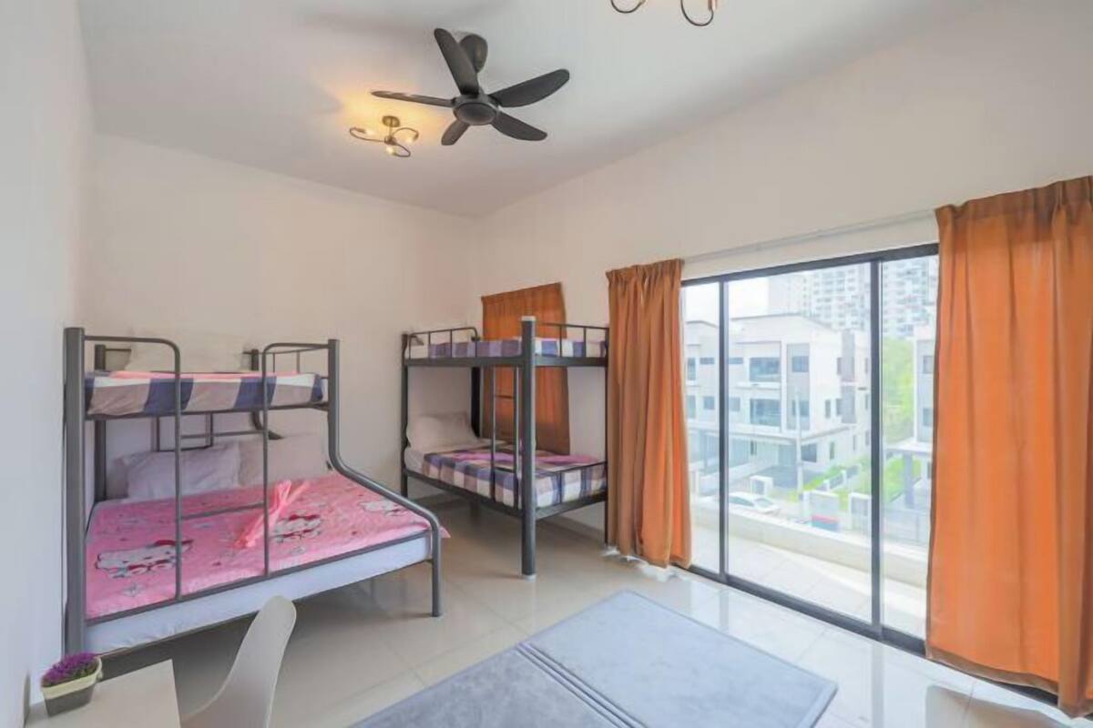 A room with bunk beds, a ceiling fan, a large window with curtains, and a view of buildings outside.