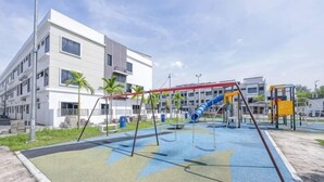 A playground with swings and slides, a building with balconies, and a clear sky. - Airport#F1#KLIA#Mitsui#Transit#INTI#NILAI#SepangF1 (Sepang)