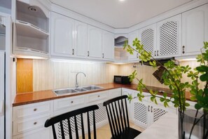 Una cocina moderna con armarios blancos, encimera de madera y una silla negra.