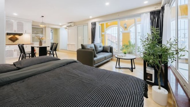 A hotel room with two beds, a sofa, a small table, and a potted plant. - VietHOME - 22 Pho Hue - Duplex 67 (Hanoi)