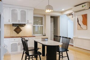 Una cocina moderna con armarios blancos, una mesa de comedor con sillas y una lámpara colgante.