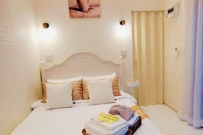 A neatly made bed with a white headboard, a small bedside table, and a wall-mounted light fixture. - Relax Pool Villa Khaoyai (Pak Chong)