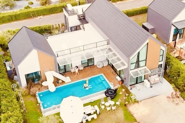 A modern house with a swimming pool, outdoor seating, and a covered patio.