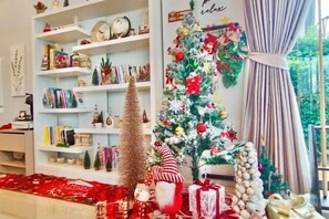 A decorated living room with a Christmas tree, shelves with books and decorations, and a red carpet. - Relax Pool Villa Khaoyai (Pak Chong)