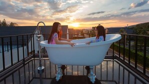 A bathtub on a balcony with a sunset view. - Relax Pool Villa Khaoyai (Pak Chong)