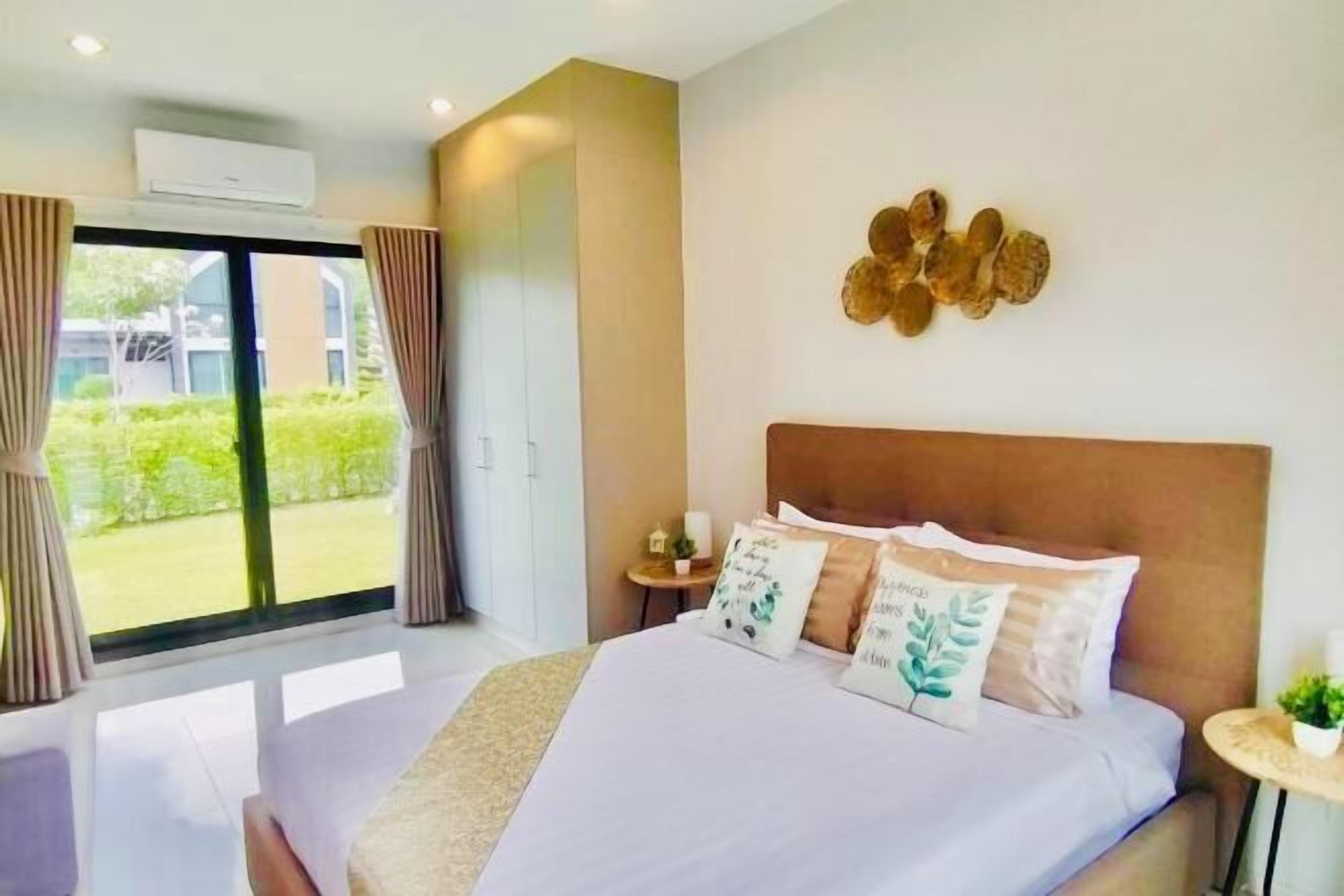 Una habitación de hotel moderna con una cama grande, vistas al exterior y una pequeña mesa con una planta.