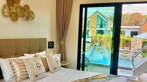 A hotel room with a bed, a view of a swimming pool, and a glass door leading to an outdoor area. - Relax Pool Villa Khaoyai (Pak Chong)
