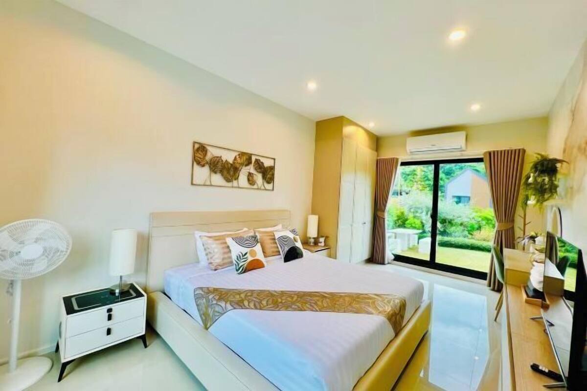 Une chambre d’hôtel moderne avec un grand lit, une table de chevet et une fenêtre avec des rideaux.