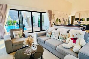 A modern living room with a sofa set, a coffee table, and a large teddy bear. - Relax Pool Villa Khaoyai (Pak Chong)