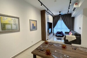 A modern living room with a dining area, a sofa, a TV, and a ceiling fan. - M Centura KL Fully Air-Conditioned 2-Bedroom Suite (Kuala Lumpur)
