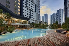 Una piscina con cubierta de madera, rodeada de edificios altos.