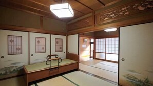 Um quarto japonês tradicional com tatames, futon de madeira baixa, portas deslizantes e um painel shoji.