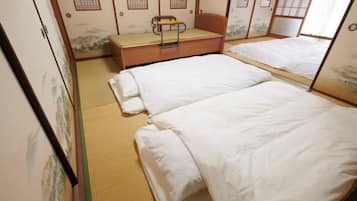 Ein traditioneller japanischer Raum mit Tatami-Bodenbelag, zwei Einzelbetten, einer hölzernen Bank und Shoji-Schiebetüren.