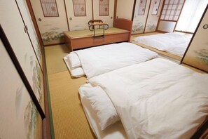 Une pièce de style japonais traditionnel, avec un sol recouvert de tatamis, deux lits simples, un banc en bois et des paravents shoji.