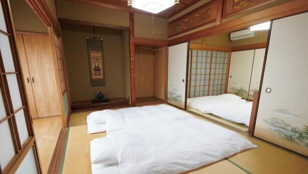 Um quarto japonês tradicional com tatames, futon, portas corrediças e um rolo pendurado.