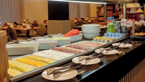 A buffet with various food options including meats, cheeses, and fruits.