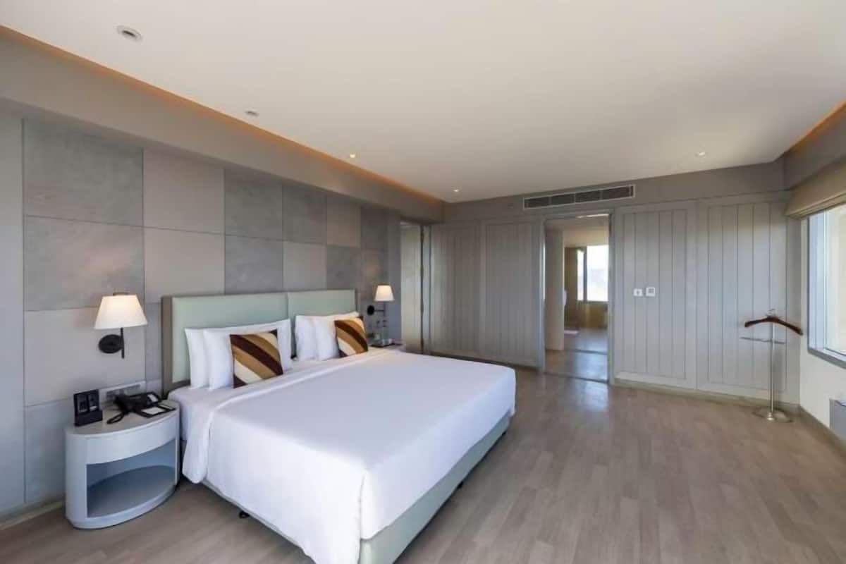 A modern hotel room with a large bed, bedside tables, and a view of the hallway.