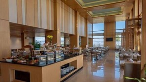 A spacious hotel lobby with a central buffet area, seating arrangements, and large windows providing natural light. - dusitD2 Fagu (Shimla)