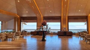 A spacious lobby with a high ceiling, seating arrangements, and a large window offering a view. - dusitD2 Fagu (Shimla)