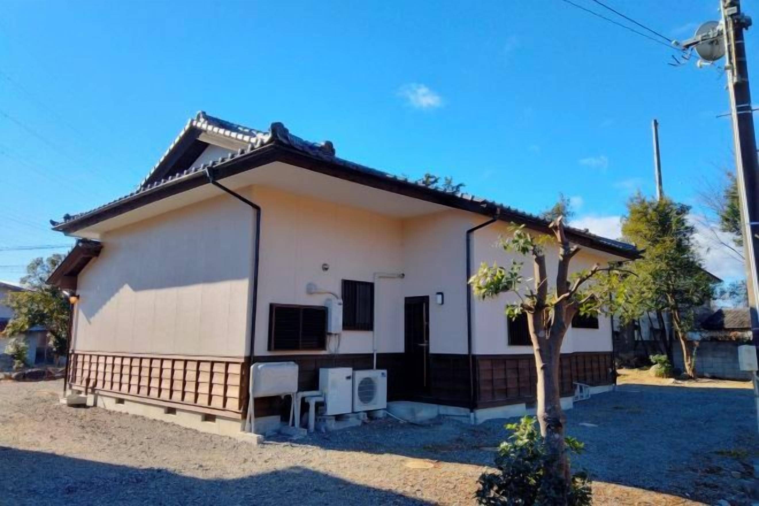 A single-story building with a tiled roof, a small porch area, and two air conditioning units on the ground floor.