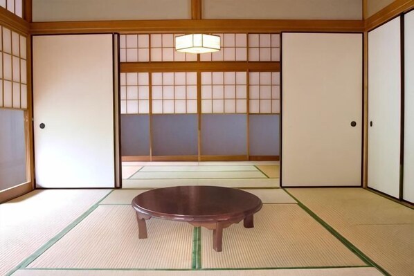 A traditional Japanese room with tatami flooring, sliding doors, and a low wooden table.