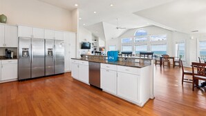 A spacious kitchen with white cabinetry, stainless steel appliances, and a large island. - SS2-Oceanfront w/7 masters, private pool & hot tub, elevator & pool table (Southern Shores)
