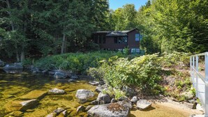 Una cabaña rodeada de un bosque tupido y un arroyo cristalino.