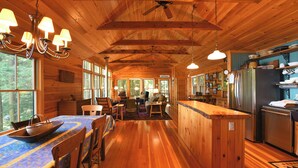 Interior de una cabaña de madera con comedor, cocina y zona de estar.