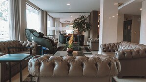 Una moderna hall d'albergo con divani in pelle, una poltrona massaggiante e una reception.