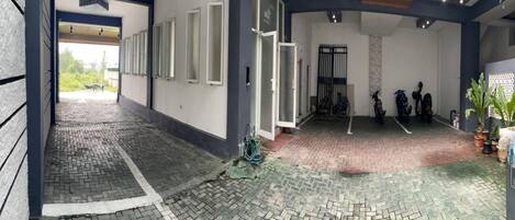 A covered outdoor area with a paved floor, a bike rack, and a potted plant.