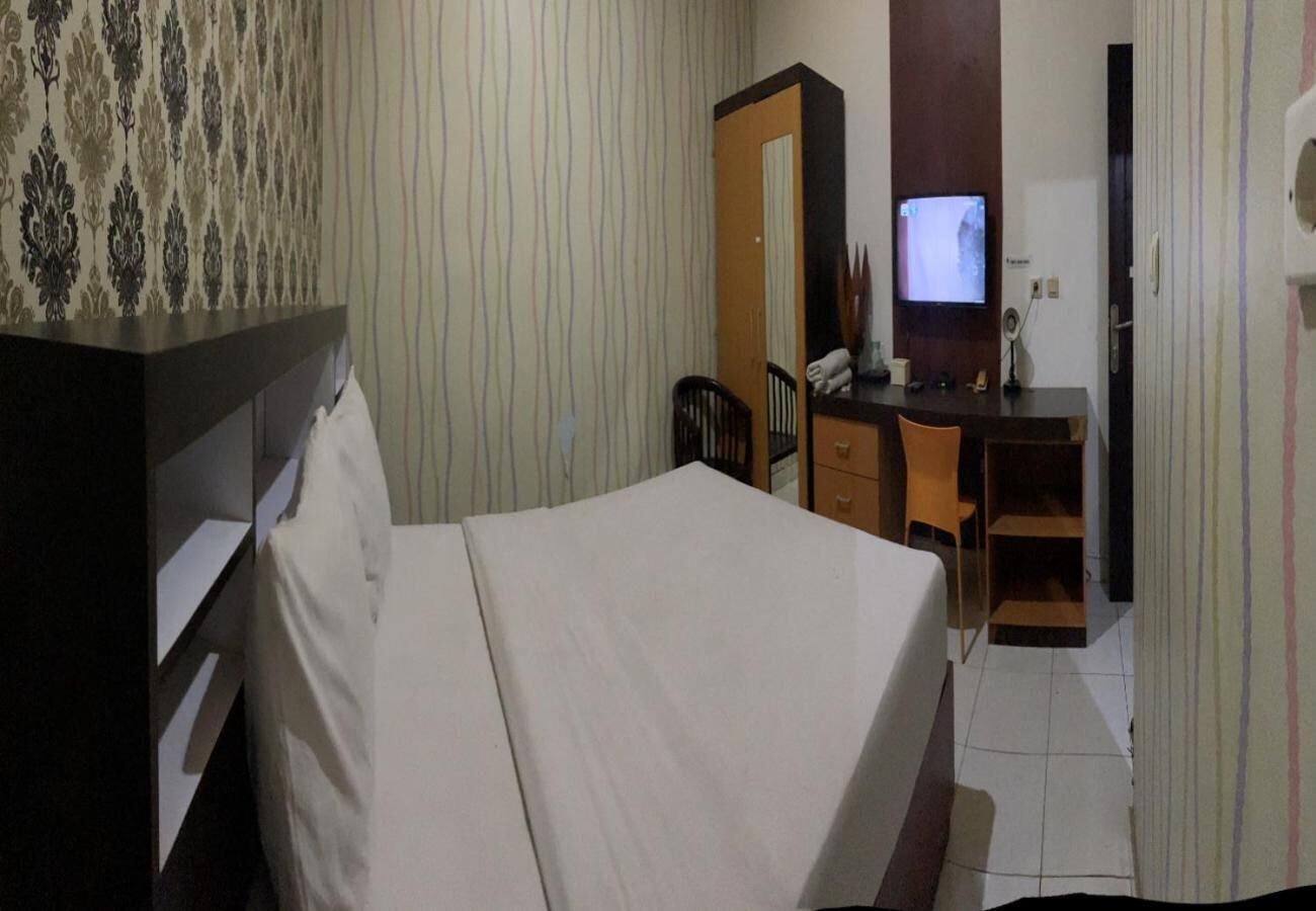 Ein Hotelzimmer mit einem Bett, einem Schreibtisch, einem Stuhl, einem Fernseher und einem Kleiderschrank.
