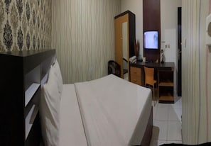 Une chambre d’hôtel équipée d  ’un lit, d’un bureau, d’une chaise, d’une télévision et d’une armoire.