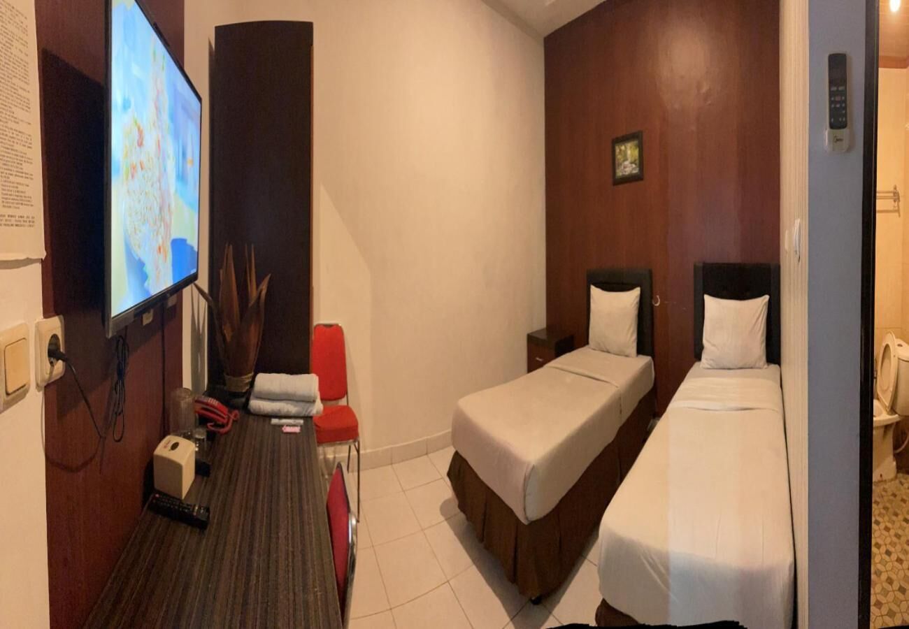 A hotel room with two beds, a TV, a desk, and a red chair.