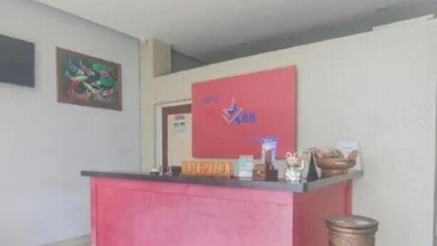 A reception desk with a red counter, a sign with the number 888, and a trash can to the right. - Hotel Star 88 (Gamping)