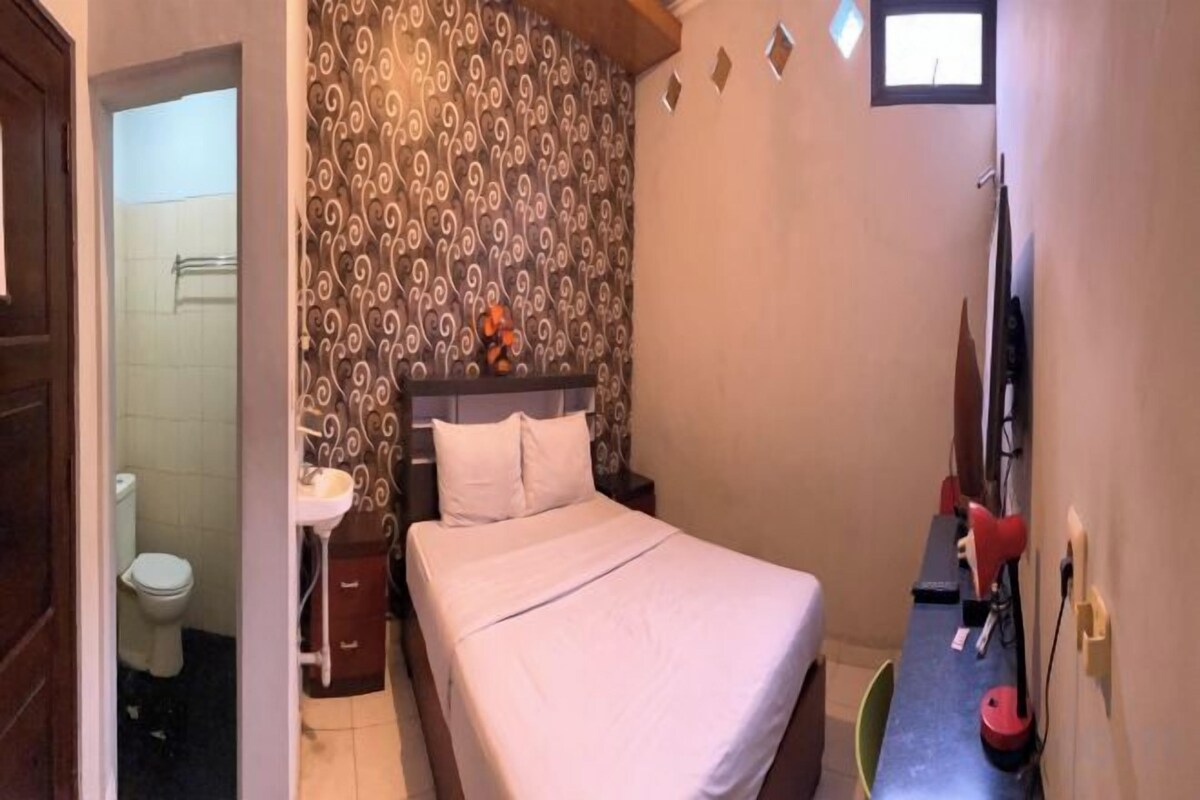 A bedroom with a bed, a nightstand, a dresser, and a window.